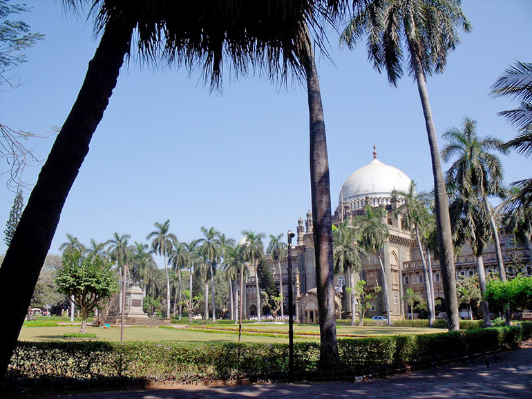 Das Chhatrapati Shivaji Maharaj Vastu Sangrahalaya Museum hinter Palmen und gepflegtem Garten.